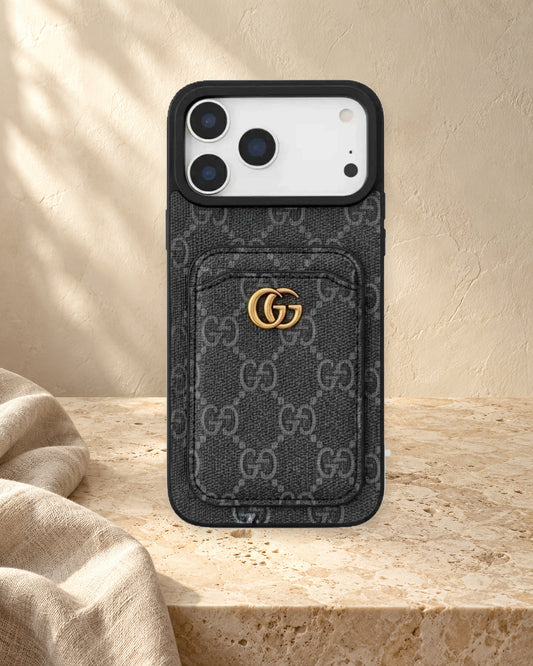 Dark GG monogram design iPhone case with a rear card pocket, gold-coloured GG emblem and a display phone in a warm ivory setting.