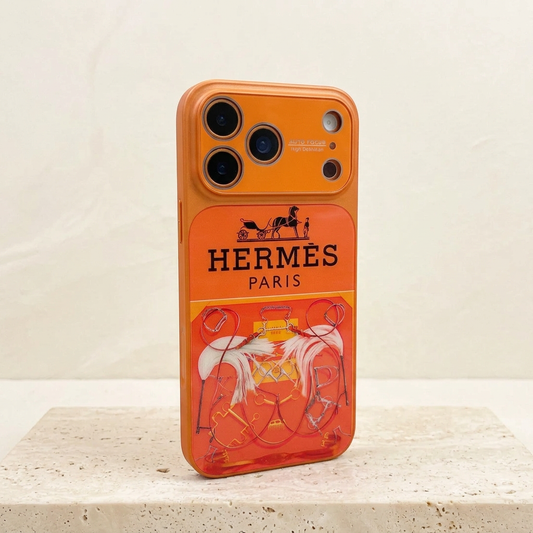 Style A orange Hermès design case standing at an angle, showing black carriage and name above a colourful equestrian print and orange camera surround.