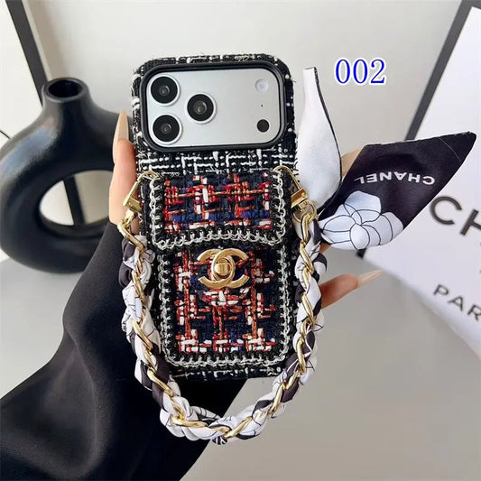 Phone case with Chanel design and chain strap held by a hand, with a Chanel box in the background.