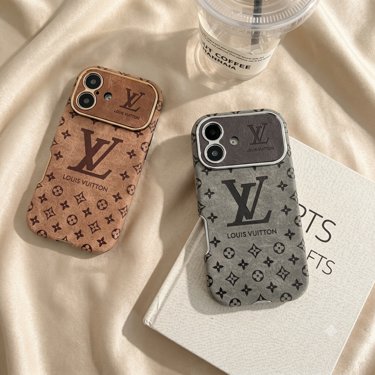 Louis Vuitton iPhone Case – Premium Leather Cover iPhone Case 17 Pro max | Black & Brown Two Louis Vuitton phone cases on a beige fabric background with a coffee cup.