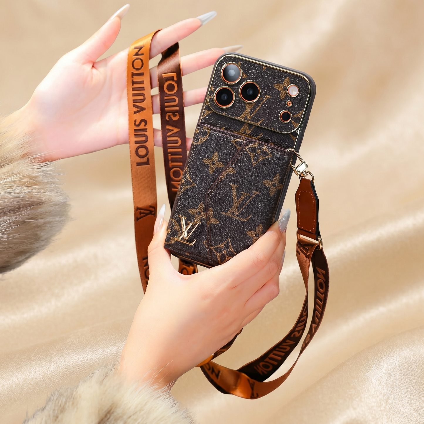Louis Vuitton iphone case with strap held by a hand on a beige background
