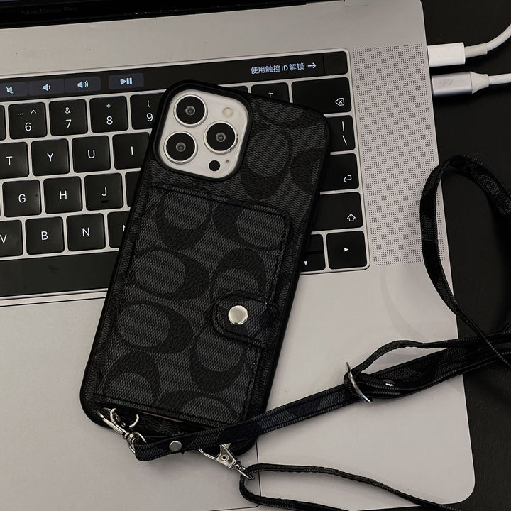 Phone case with Coach logo held by a hand Black patterned phone case with strap on a laptop