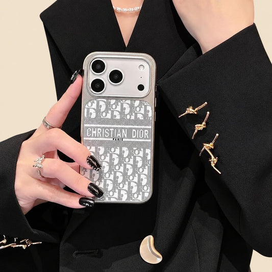 Gray Christian Dior monogram design iPhone case held against a black outfit, showing a name band and silver-coloured trim.