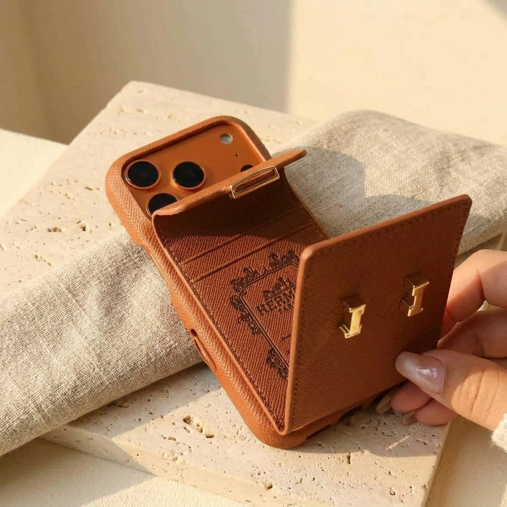 Brown iPhone case with the rear card pocket flap open, held over cream travertine and linen.