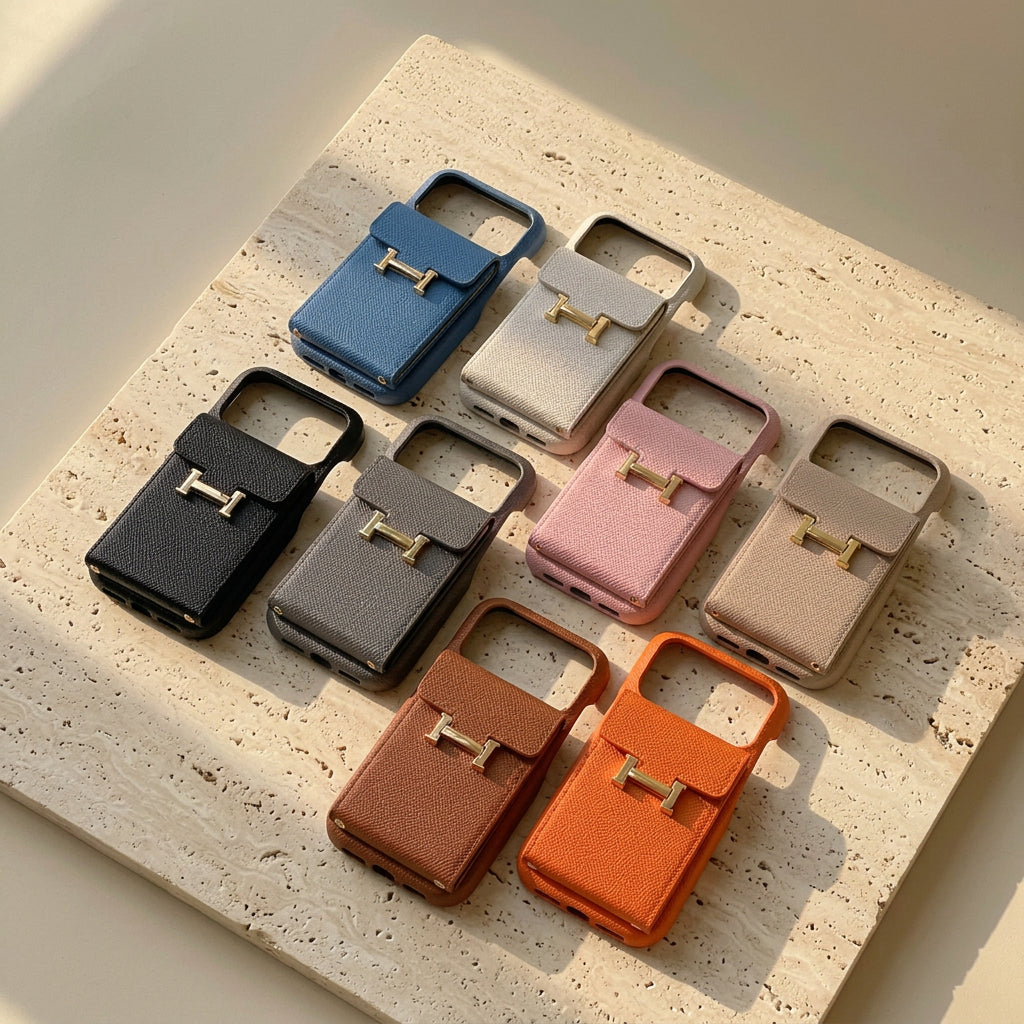Eight colours of the H buckle design card pocket iPhone case laid out on cream travertine.