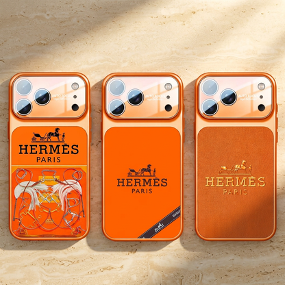 Three orange Hermès design cases side by side: equestrian print, black carriage motif with diagonal ribbon graphic, and textured gold-tone carriage motif.