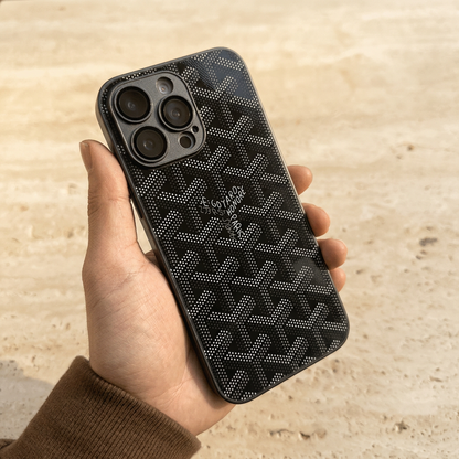 Glossy black back cover held in one hand, showing contrasting grey and white dotted chevrons and a small central name detail.