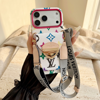 White multicolour monogram rear-pocket case with pink camera trim, gold-tone clasp and long pale wordmark strap, held by a manicured hand.