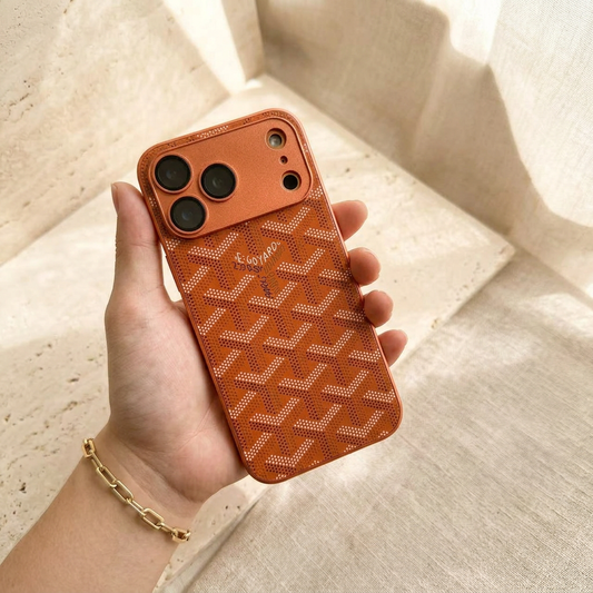 Hand-held copper-orange chevron-design case with a glossy dotted back, central name detail and a wide orange camera panel.