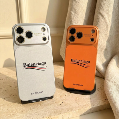 Silver-toned White and orange Balenciaga wordmark design back covers standing side by side on black display stands.