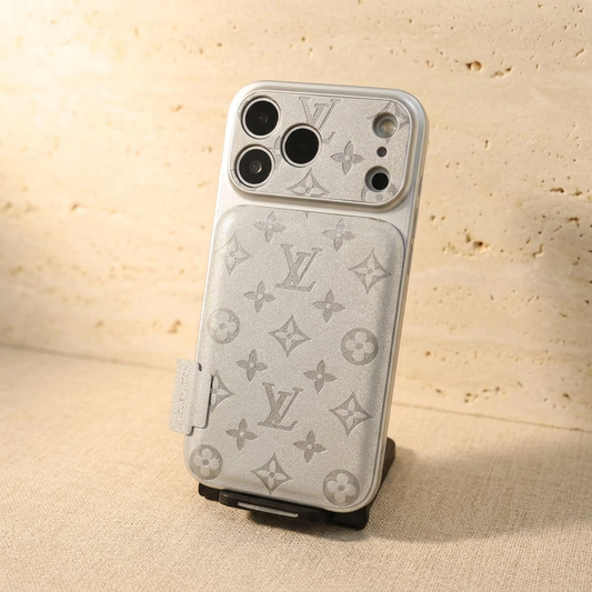 Upright Silver Louis Vuitton tonal monogram design iPhone case on a black display stand, showing grey motifs, patterned camera surround and a rectangular side name tab.