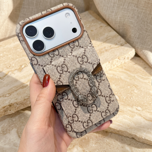 Chain style rear view with beige-and-brown GG pattern, brown envelope-pocket inserts, ornate silver-tone oval detail and wide camera opening.