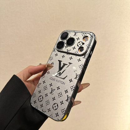 Silver Louis Vuitton monogram design iPhone case held at an angle, showing a wide patterned camera panel, large LV motif and dark reflective side rim with control details.