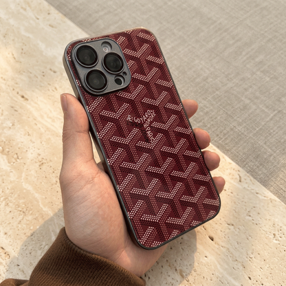 Burgundy-red back cover held in one hand, with light dotted chevrons, a central name detail and a dark camera surround.