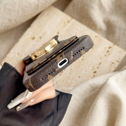 Tight diagonal close-up of the brown monogram case bottom, showing the silver-rimmed port opening, rows of small holes and rear-pocket thickness.