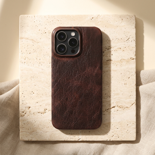 Dark brown creased-grain iPhone back cover fitted on a display phone, showing its plain rear panel and camera opening.