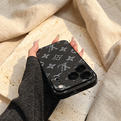 Tilted rear view of the black textured case with large grey LV and floral motifs, a matching camera panel and dark perimeter edging.