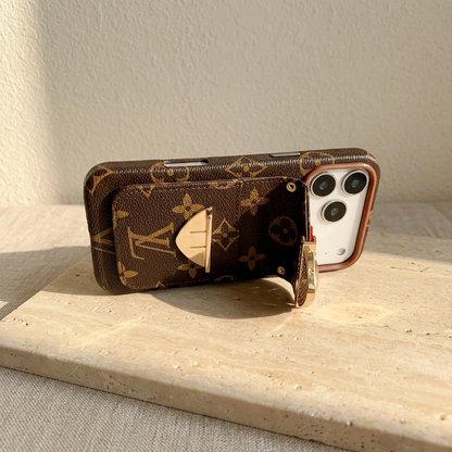 Brown monogram case resting in landscape orientation with its rear-pocket flap open, showing the clasp parts, side controls and display-phone camera panel.