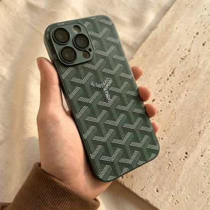 Deep forest-green chevron case held in a brown knit sleeve, showing light dotted motifs and a dark green camera surround.