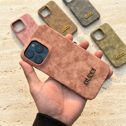 Peach-pink distressed-look Gucci design case held diagonally, with a gold-tone name, blue display phone camera and five comparison cases behind.