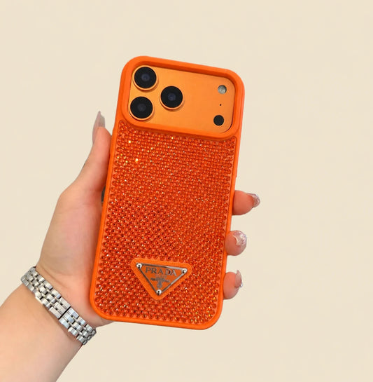 Hand holding the orange Prada triangle design iPhone case with a sparkling studded back, matching trim and an orange display phone.